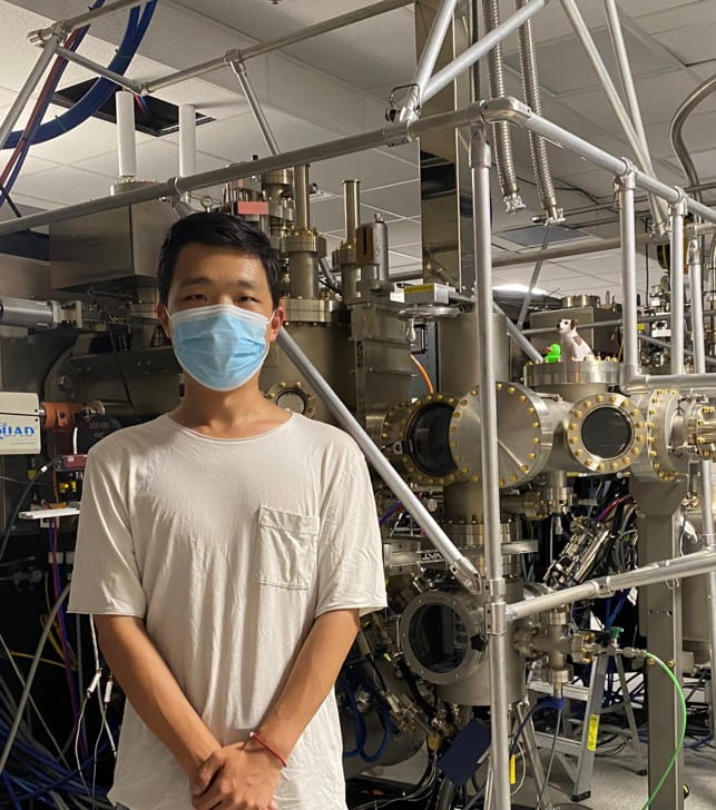 Yongchen posing in front of a Molecular Beam Epitaxy machine